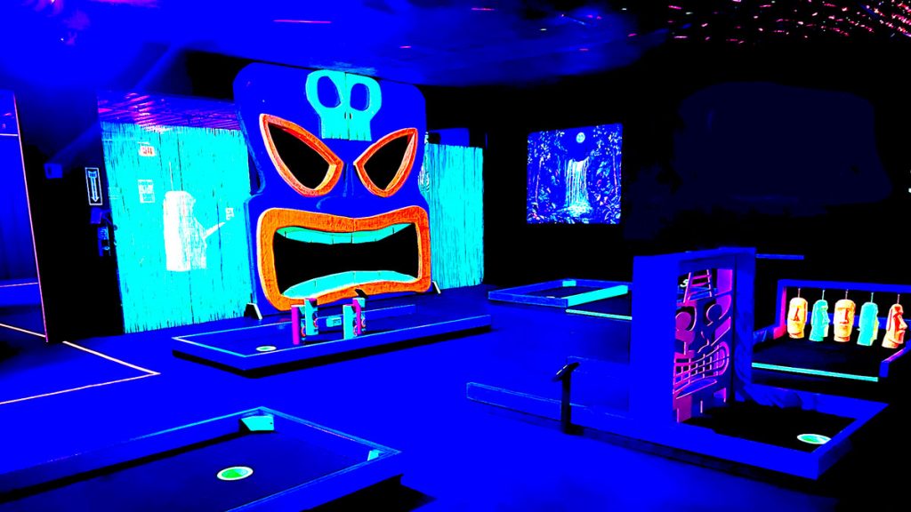 A glowing blacklight mini golf course with a tiki theme.