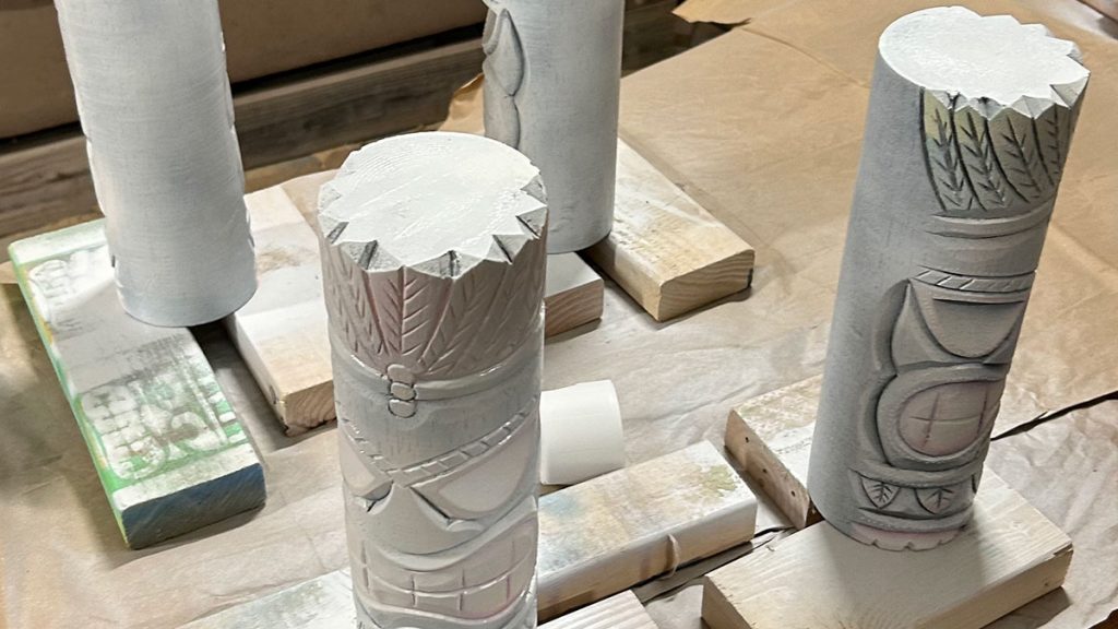 Priming small tiki statues.