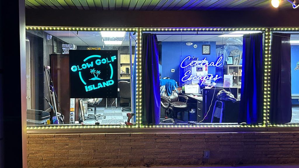 A sign at night on the front of the Glow Golf Island building.