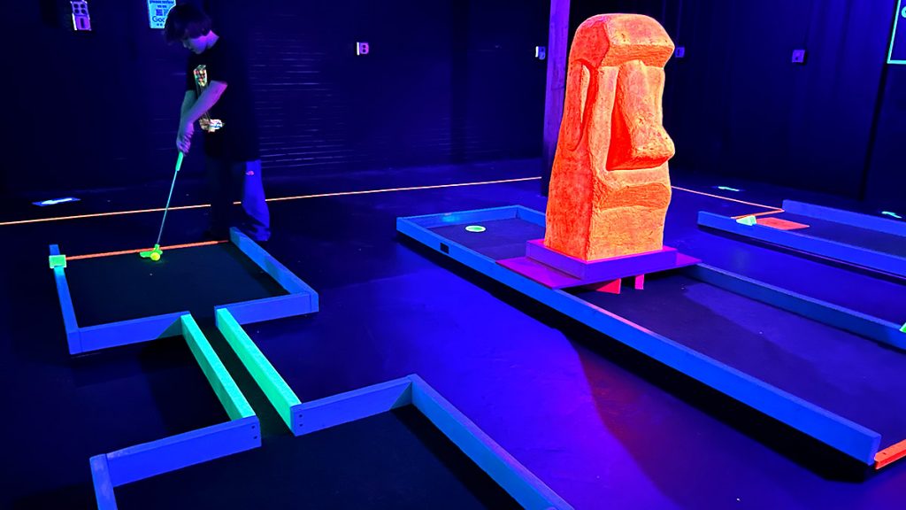 A player putting on a mini golf hole.