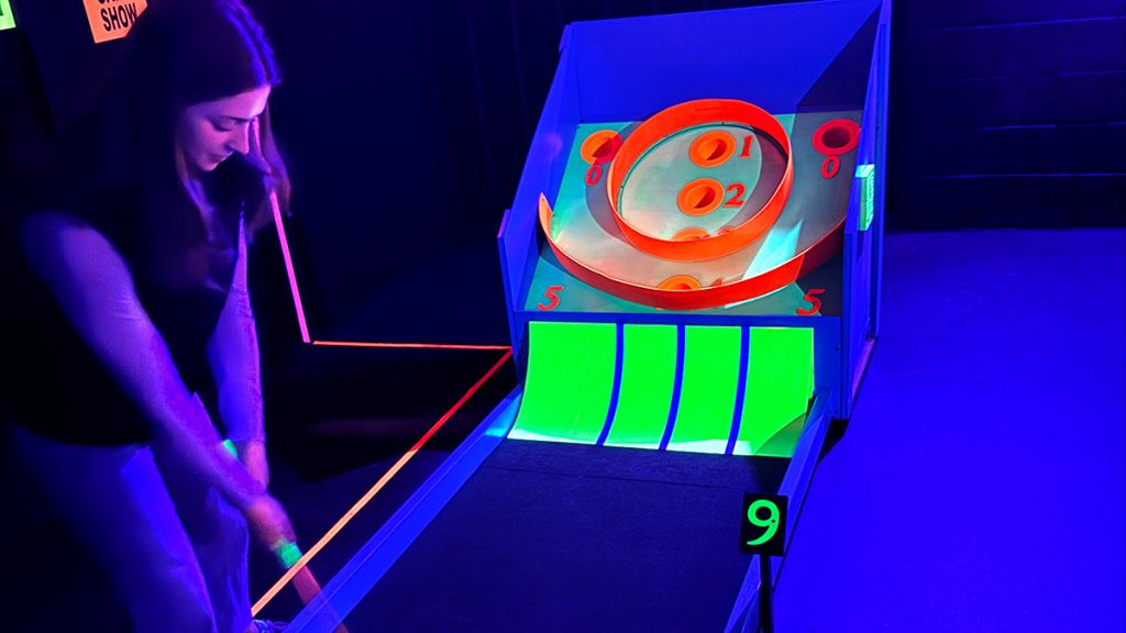 A skee-ball mini golf hole with golfer.